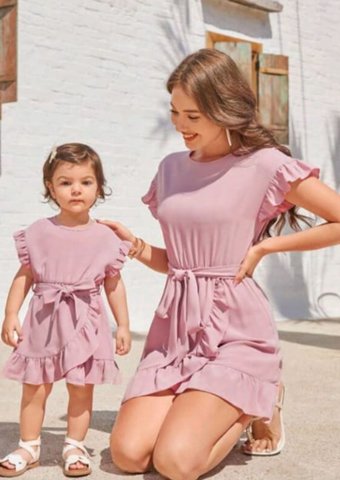 Madre e hija con vestidos rosas a juego sobre fondo suave, representando estilo y ternura en moda infantil y maternidad